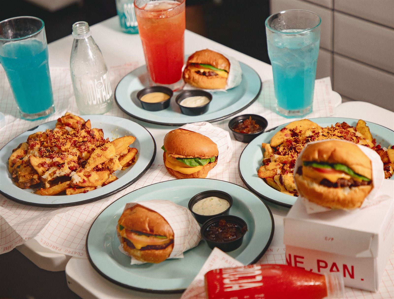 Mesa con burgers y sodas Cuatro Paredes